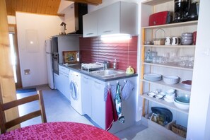 A compact kitchen with a washing machine, a sink, and a dining area with a table.