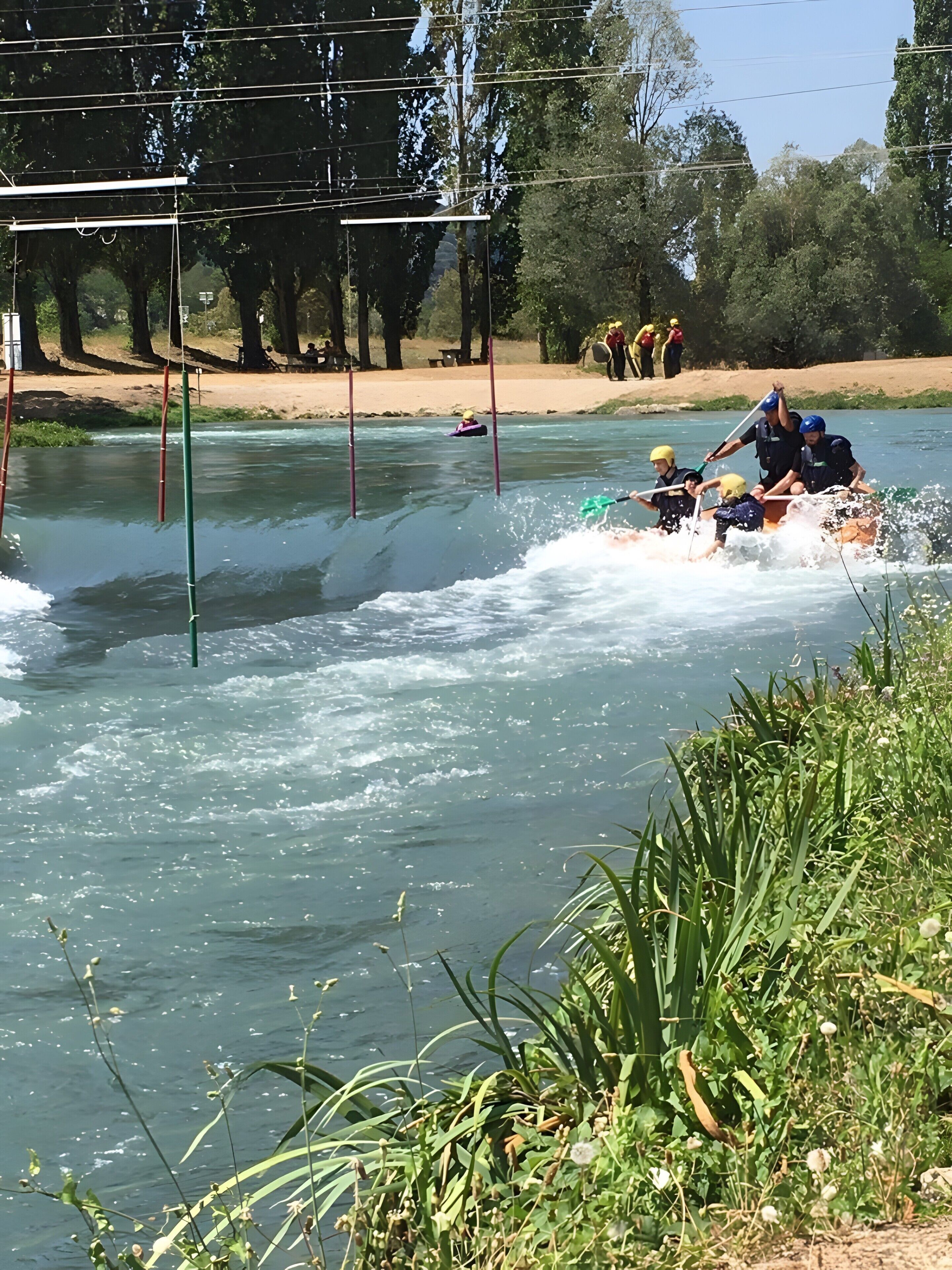 Eine Flusslandschaft mit einem Floß und Personen, die Helme tragen.