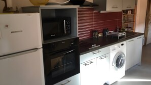 Eine moderne Küche mit Einbauofen, Mikrowelle und Geschirrspüler, sowie einer Waschmaschine.