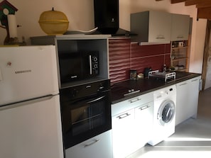A modern kitchen with a built-in oven, microwave, and dishwasher, along with a washing machine. - Gîte des Buis de l'Ain – Nature, Peace & Tranquility (Groslée-Saint-Benoit)