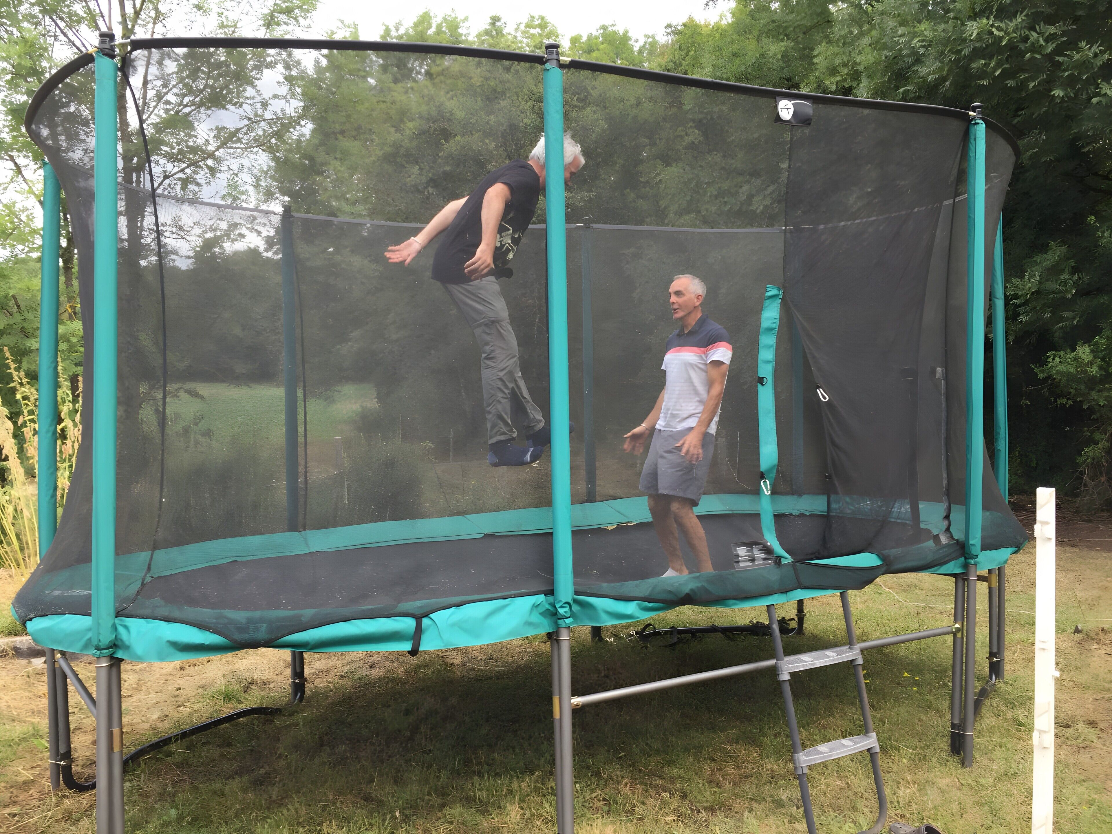 Un trampolín con recinto de malla de seguridad en un entorno exterior.