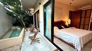 A bedroom with a large bed, a window with curtains, a nightstand, and a small table. - Modern duplex with private pool + 2 bicycles / 7 minutes from Tulum Beach (Tulum)