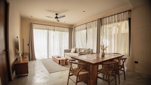 A spacious living room with a wooden dining table and chairs, a sofa, and a ceiling fan. - Modern duplex with private pool + 2 bicycles / 7 minutes from Tulum Beach (Tulum)