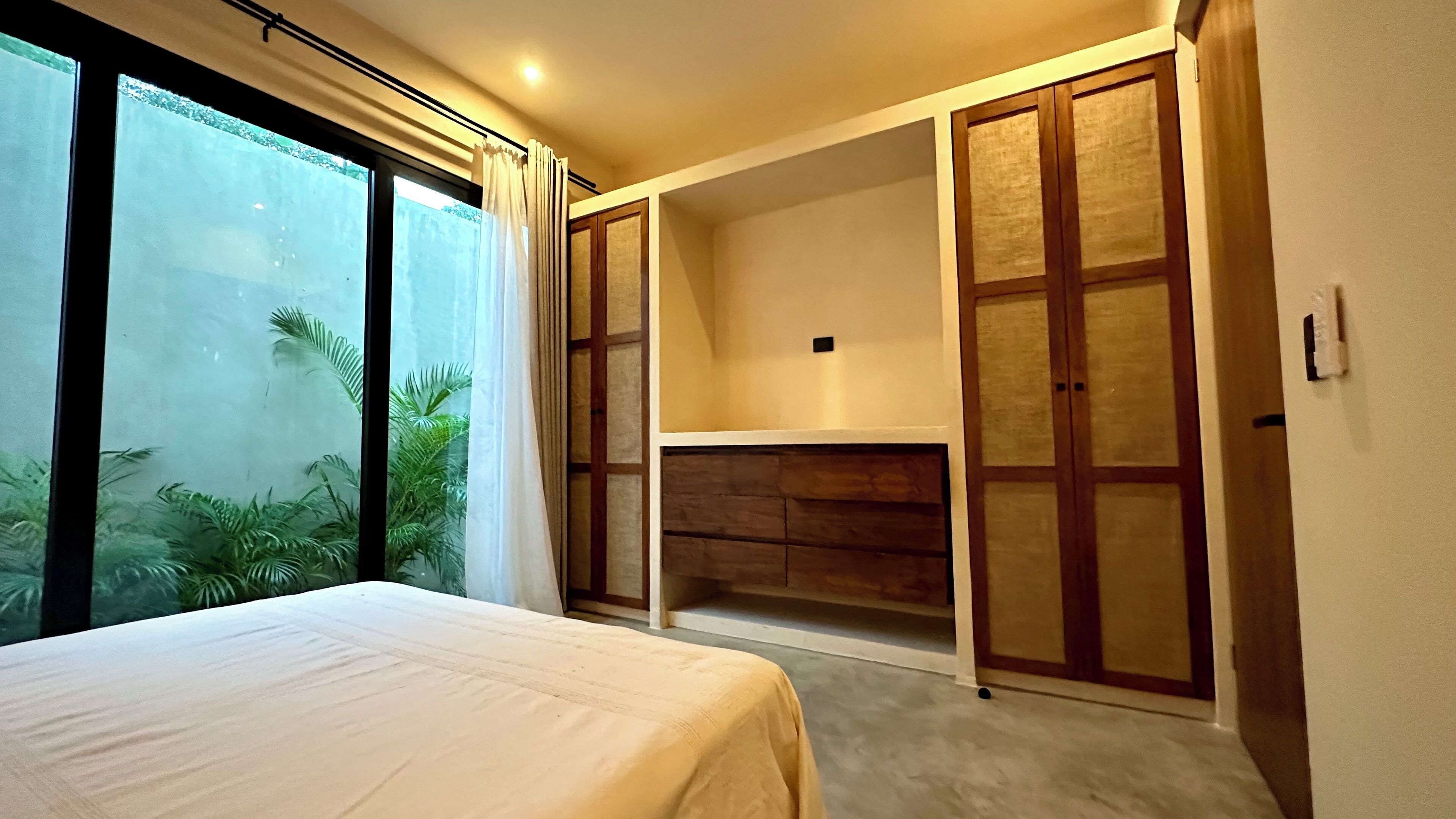 A bedroom with a bed, a desk, and a wardrobe.
