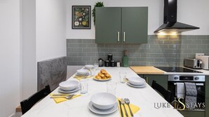 A modern kitchen with grey cabinets, a black range hood, and a tiled backsplash. - Luke Stays - Grace Street (Tyne and Wear)