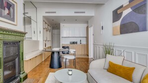 Ein modernes Wohnzimmer mit Kamin, Essbereich und Küche mit weißen Schränken.