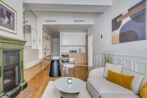 A modern living room with a fireplace, a dining area, and a kitchen with white cabinets. - A Wonderfull 2-BA - Palais Royal (Paris)