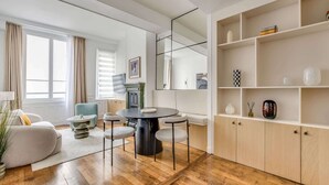 Ein modernes Wohnzimmer mit rundem Tisch, Stühlen, einer Couch und einem Bücherregal.
