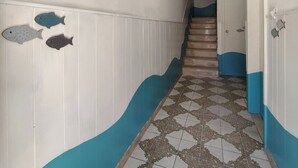Ein Flur mit gefliestem Boden, einer Treppe und Fischornamenten an der Wand.