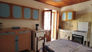 Eine Küche mit Holzausstattung, einem Kühlschrank, einem Herd und einem Esstisch mit Tischdecke.