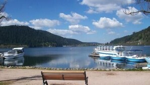Une vue sur le lac, avec des bateaux amarrés, un banc et un ciel dégagé.