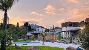 Una moderna casa con piscina, immersa in un giardino curato e affiancata da grandi rocce.