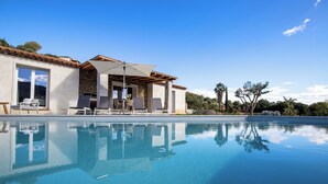 Un'area a bordo piscina con un edificio in pietra, posti a sedere all'aperto e vista diretta sulla piscina.
