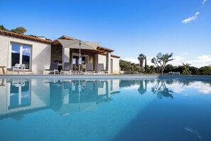 A poolside area with a stone building, outdoor seating, and a clear view of the pool. - Luxury villa in Sardinia for 8 people with private pool, garden and wifi (Sardegna)