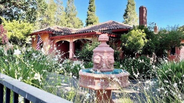 Ein Garten mit einem Brunnen, einem Pavillon und einem Backsteinhaus.