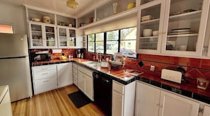 A kitchen with white cabinets, a black countertop, and a window providing a view outside.