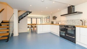 Una cocina moderna con armarios blancos, una estufa negra y una escalera de madera.