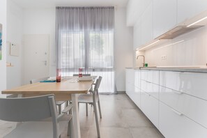 A modern kitchen with white cabinets, a wooden table, and a window with sheer curtains. - Apartment 'Arena Suite Fuengirola' with Wi-Fi and Air Conditioning (Fuengirola)
