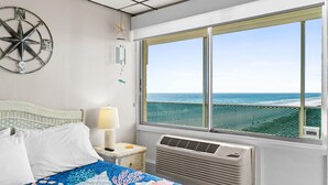 Quarto com cama, janela vista para o oceano, relógio na parede e decoração de estrela-do-mar.