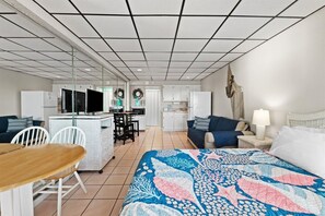 Ein Hotelzimmer mit einem Bett, einem Esstisch, Stühlen, einer Küchenzeile und einer Wohnbereich mit einer Couch und einer Lampe.