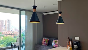 Une cuisine moderne dotée d’un grand îlot central, de luminaires suspendus, d’une machine à café et offrant une vue sur la ville.