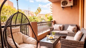 Ein Balkon mit einer Hängematte, einem Korbssessel und einem kleinen Tisch mit einer Pflanze.