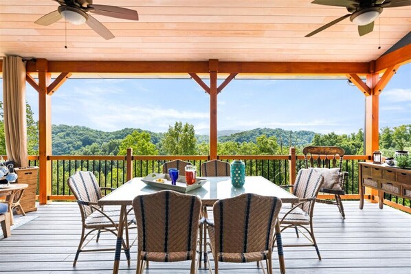 Eine überdachte Terrasse mit Tisch und Stühlen, mit Blick auf eine bewaldete Landschaft.