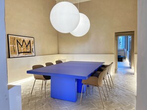 Un comedor moderno con una mesa azul, paredes color beige y una lámpara colgante grande.