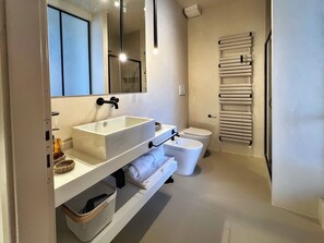 Een moderne badkamer met een witte wasbak, toilet en handdoekhouder.