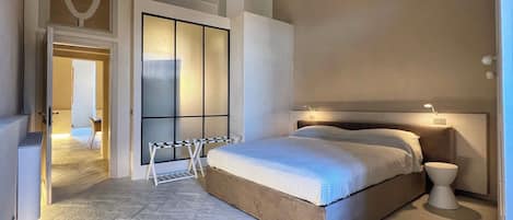 Een slaapkamer met een bed, nachtkastje en een raam met zonwering.
