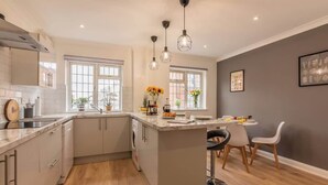 A modern kitchen with a central island, pendant lighting, and a dining area with chairs. - 3BR Luxury Chic Spacious House w/Parking -Sleeps 7 (Southampton)