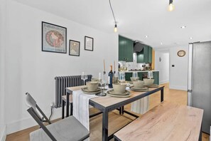 Een moderne keuken met groene kastjes, een eettafel gedekt met borden en glazen, en een radiator aan de muur.