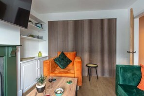 Een woonkamer met een bank, een salontafel, een televisie en een gestreepte wand.