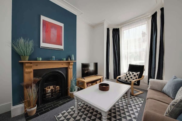 Ein Wohnzimmer mit Kamin, Fernseher, Sofa und Couchtisch.