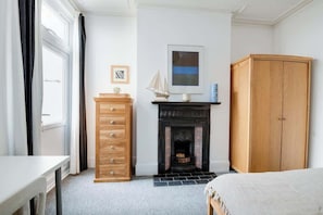 Ein Schlafzimmer mit Kamin, Kleiderschrank, Schreibtisch und Bett.
