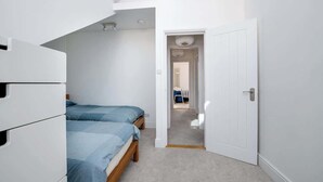 Ein Schlafzimmer mit zwei Betten, einem weißen Kleiderschrank und einer Tür zu einem anderen Raum.