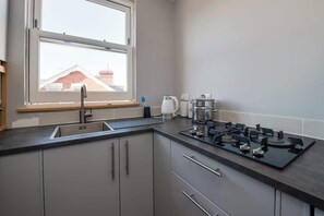 A modern kitchen with a gas stove, a sink, and a window overlooking a residential area.