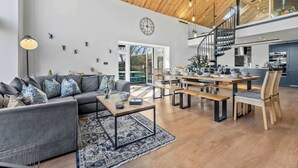 Ein geräumiger Wohnbereich mit Sofa, Couchtisch und Esstisch. Eine Treppe führt zu einer oberen Ebene.