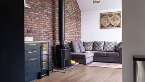 Un salon avec une cheminée en briques, un canapé et un meuble.