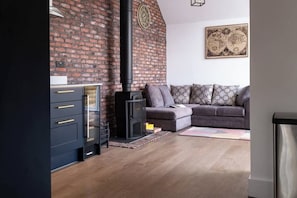 Ein Wohnzimmer mit Kamin aus Backsteinen, einer Couch und einem Schrank.