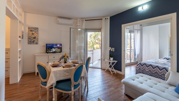 A compact living space with a dining area, a sofa, a TV, and a balcony. - GuestHost - Cozy Apartment with Terrace in Sanremo (Sanremo)