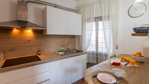 A modern kitchen with a wooden countertop, stainless steel sink, and a built-in range hood. - GuestHost - Cozy Apartment with Terrace in Sanremo (Sanremo)