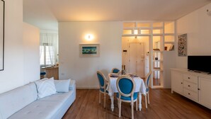 A compact living space with a dining area, a sofa, a TV, and a bookshelf. - GuestHost - Cozy Apartment with Terrace in Sanremo (Sanremo)