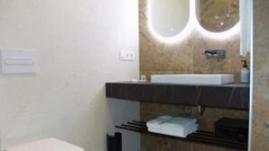 A modern bathroom with a white toilet, a marble sink vanity, and a towel rack.