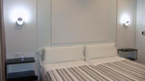 A hotel room with a bed, nightstands, and wall-mounted lights.
