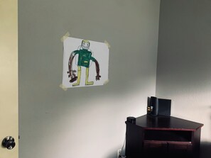 Un mur orné d’un dessin, fixé à l’aide de ruban adhésif, représentant un personnage.