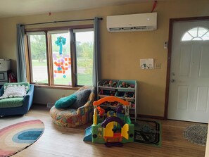A room with a blue chair, a colorful bean bag, a toy storage unit, and a window with a view of greenery. - Easy access to scenic North Shore and WI South Shore - Kids and Pets welcome!! (Superior)