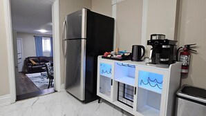 Eine Küche mit Kühlschrank, Kaffeemaschine und Mülleimer.