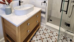 A modern bathroom with a white sink, wooden vanity, and a glass shower enclosure. - Family Beach House 4 blocks from Beach (Sea Girt)
