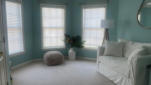A room with teal walls, a white sofa, a round mirror, and a white lamp. - Family Beach House 4 blocks from Beach (Sea Girt)